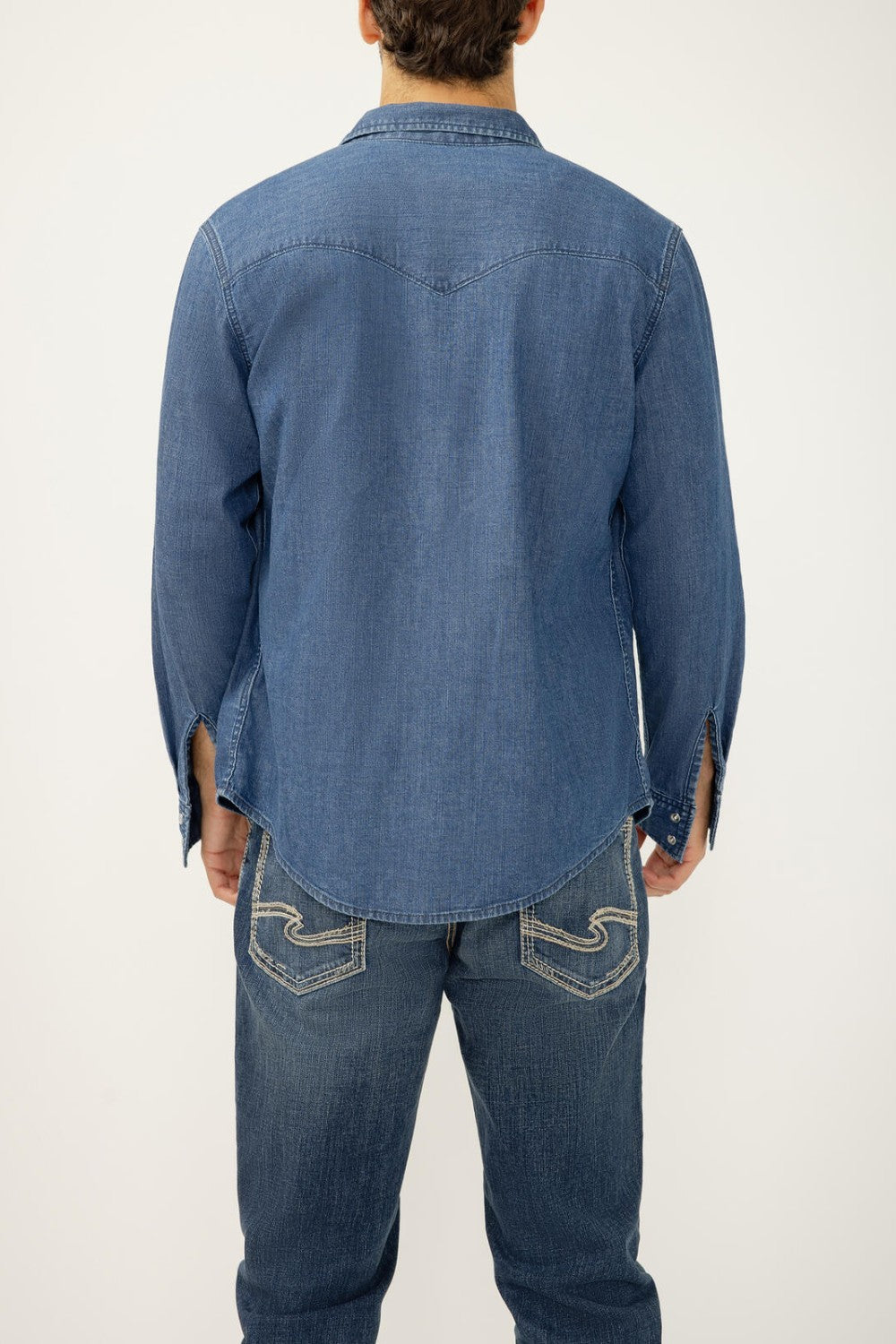 Person wearing a blue denim shirt and jeans on a white background