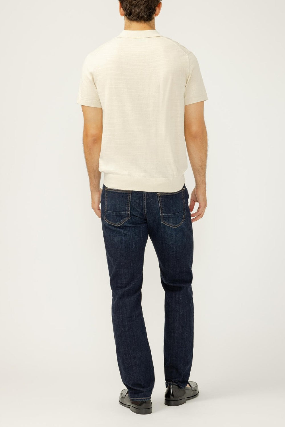 Man wearing a white t-shirt and dark blue jeans on a white background