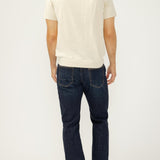 Man wearing a white t-shirt and dark blue jeans on a white background