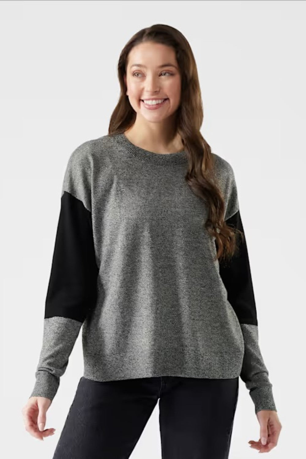 Woman wearing a gray sweater with black sleeves on a white background