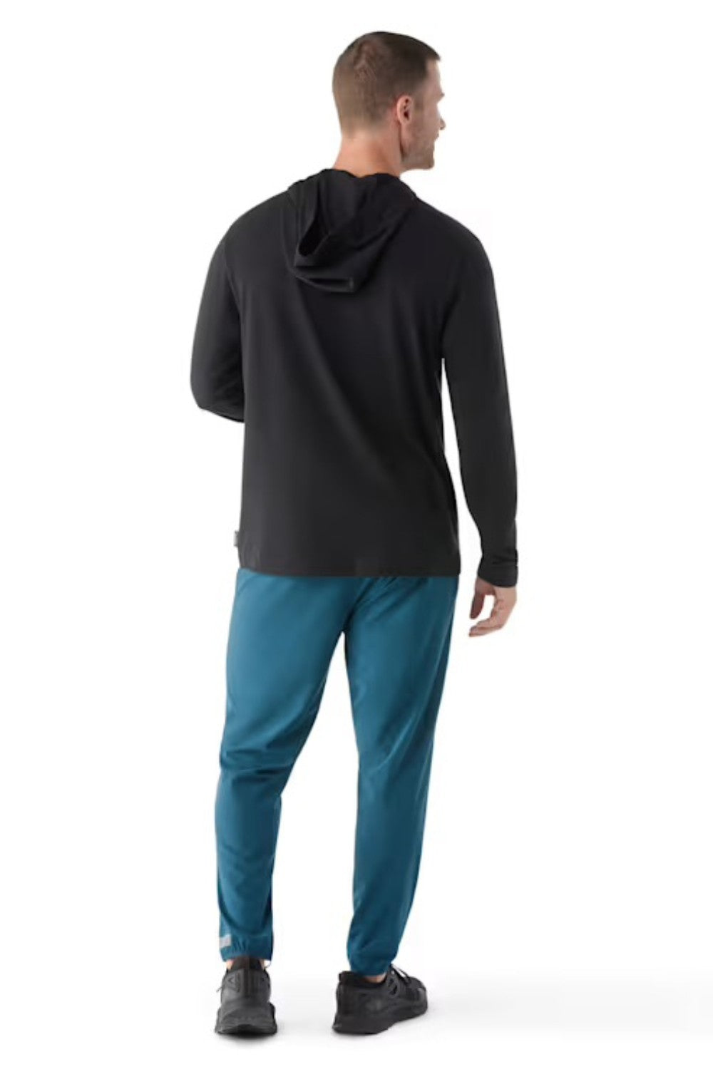 Man wearing a black hoodie and blue pants on a white background