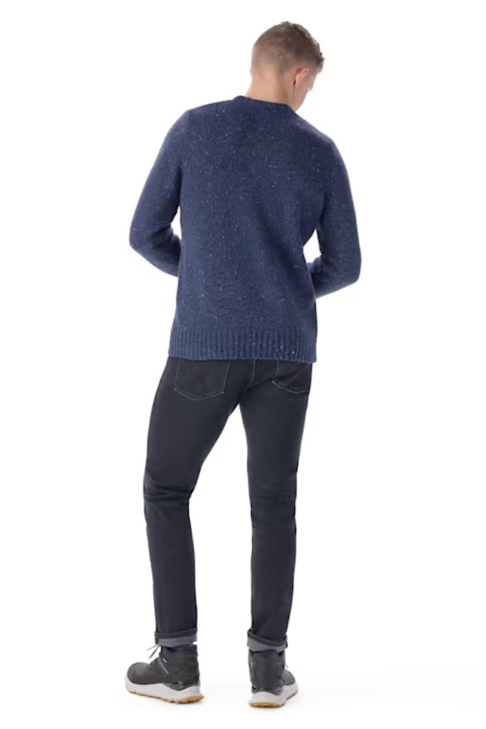 Man wearing a blue sweater and dark jeans on a white background