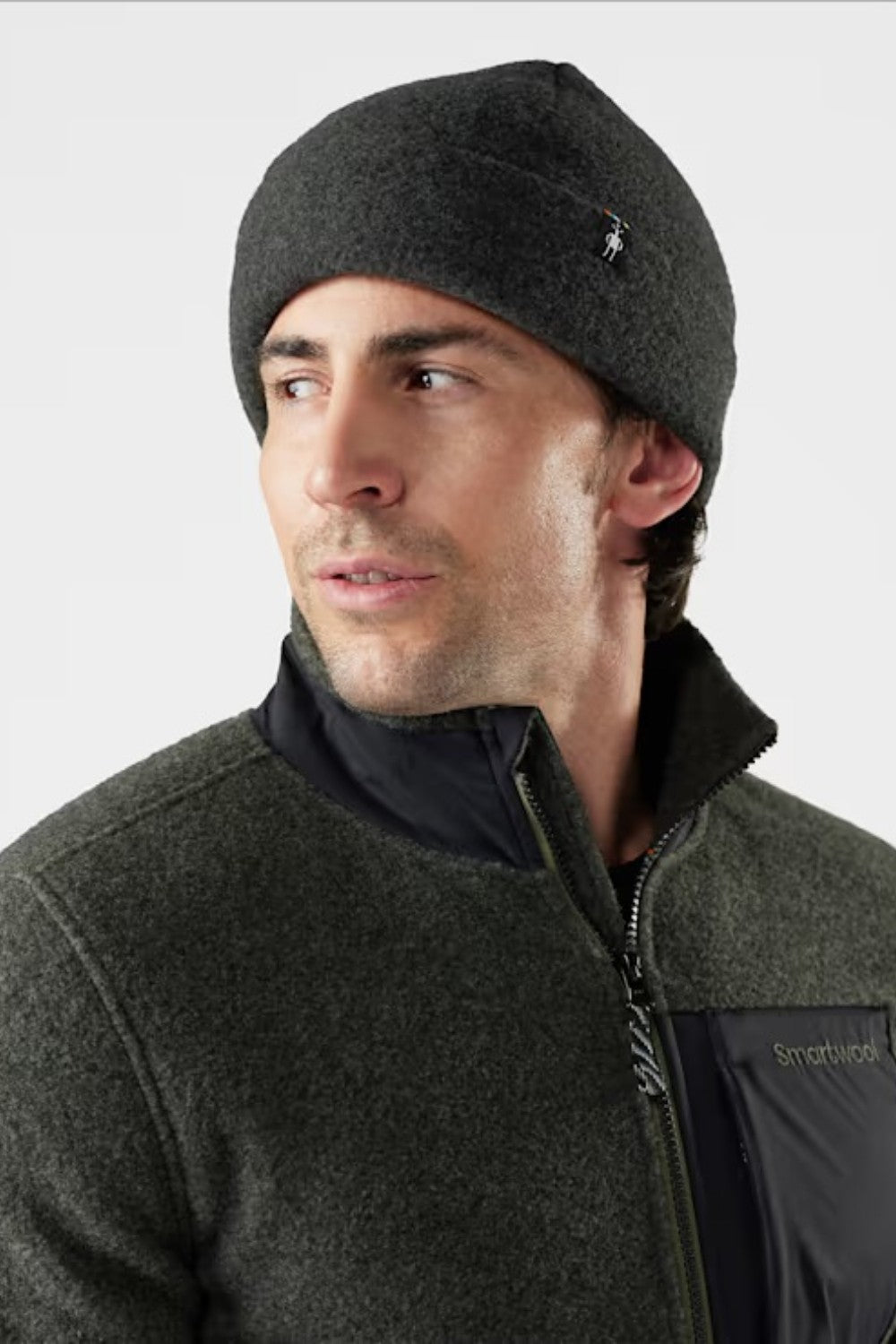 Man wearing a dark gray beanie and jacket on a light gray background