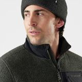 Man wearing a dark gray beanie and jacket on a light gray background