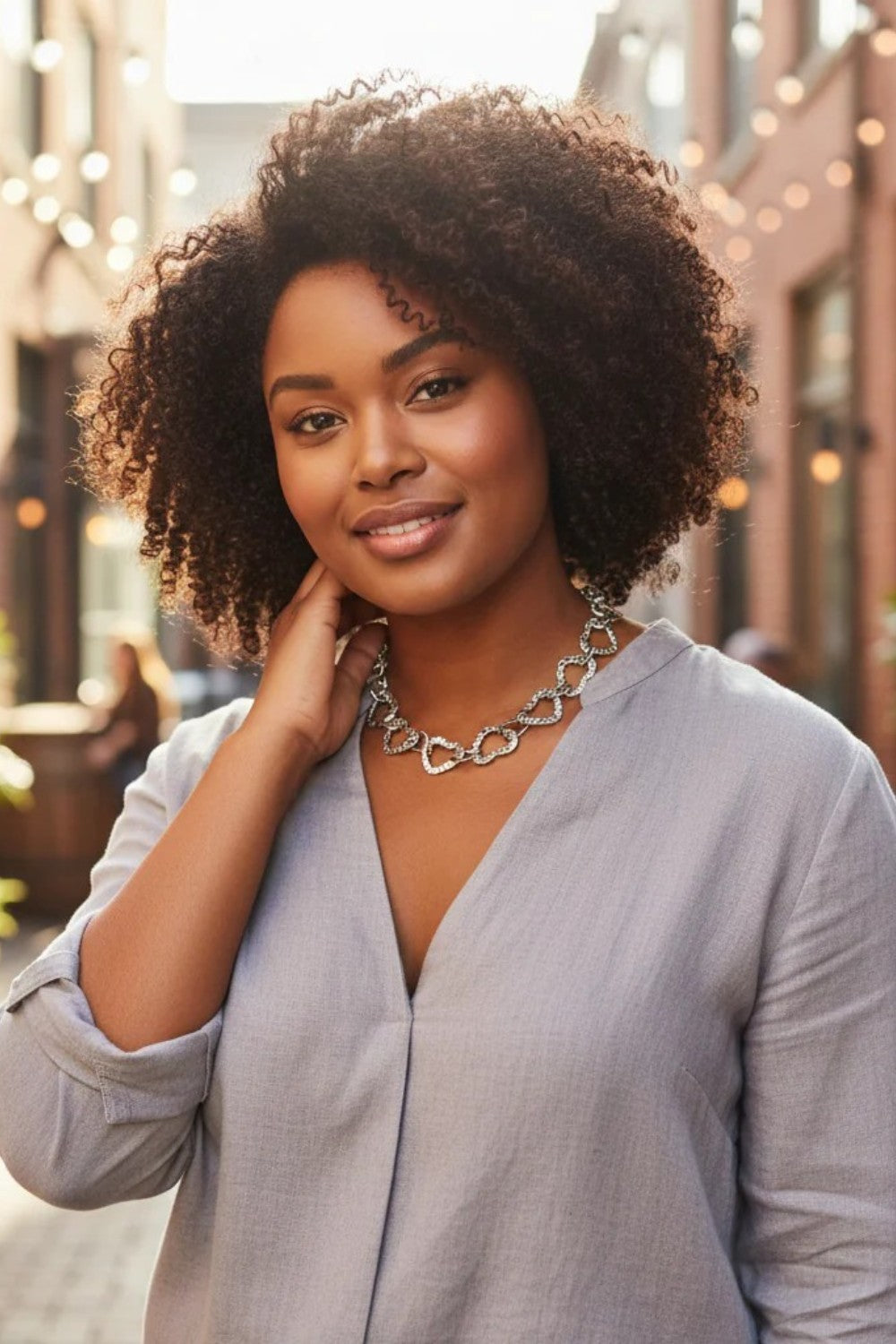 Woman wearing a silver chain necklace outdoors with blurred background