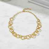 Gold necklace with circles looped together on marble surface