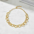 Gold necklace with circles looped together on marble surface