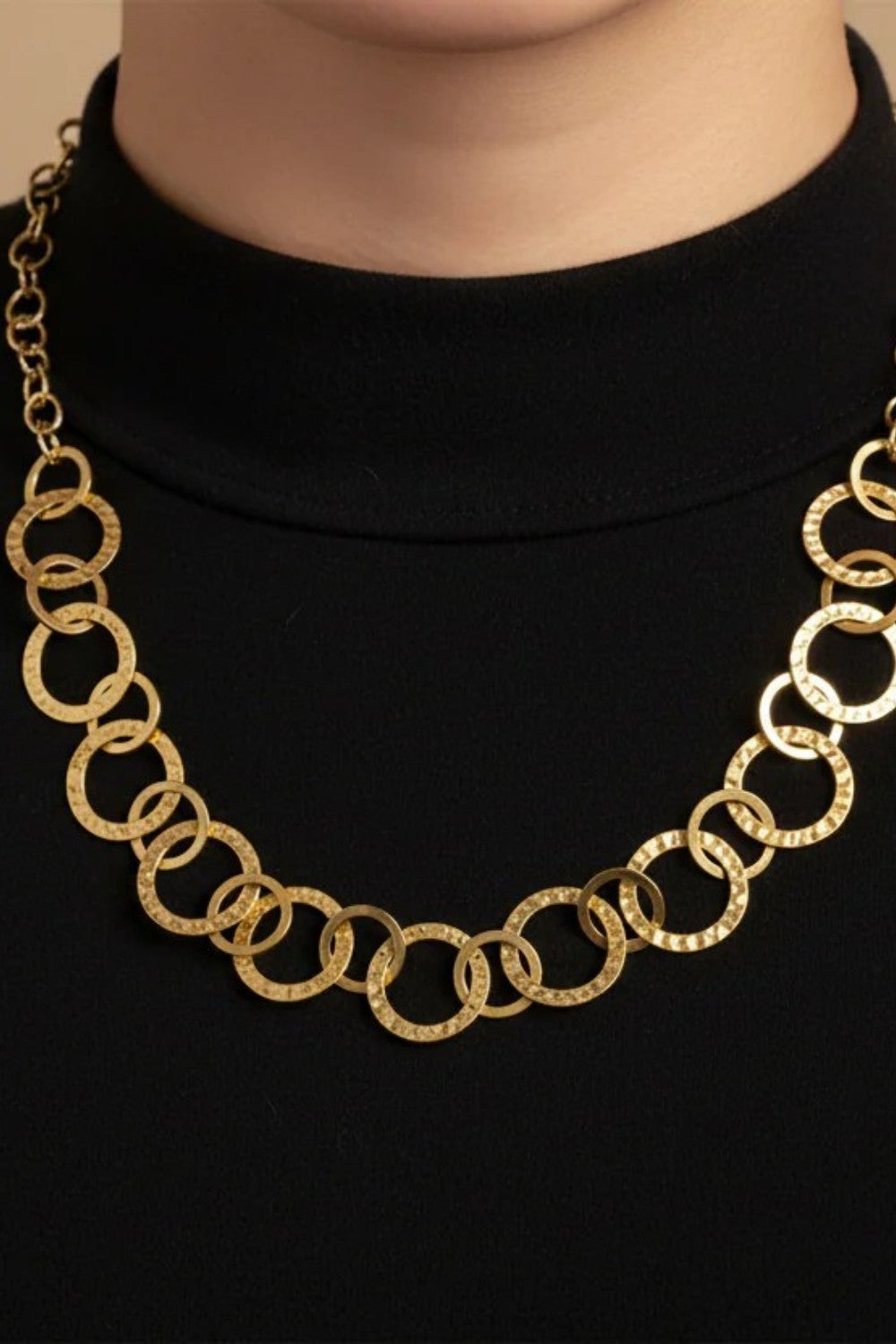 Gold necklace with circles looped together worn on a black top