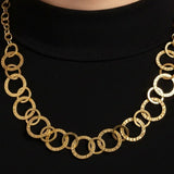 Gold necklace with circles looped together worn on a black top