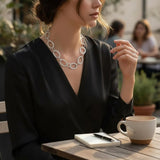 Woman sitting at an outdoor cafe table with a cup of coffee and notebook.
