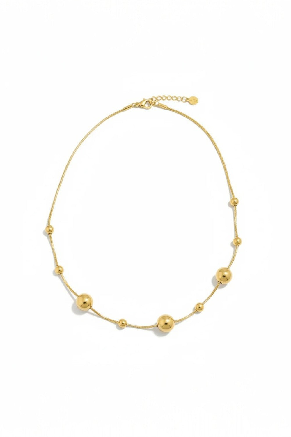 Gold necklace with spherical beads on a white background