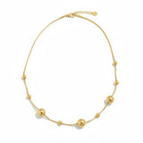 Gold necklace with spherical beads on a white background