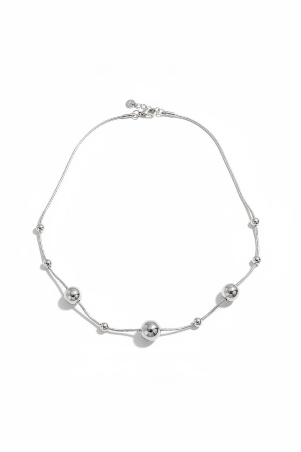 Silver necklace with spherical beads on a white background