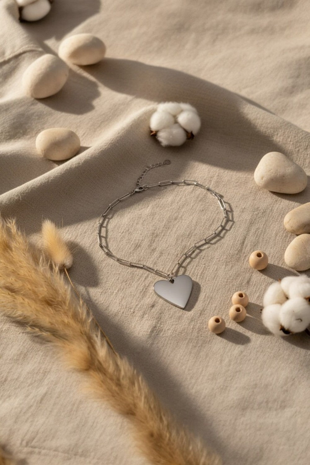Heart-shaped pendant necklace on a textured surface with cotton and stones