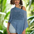 Woman wearing a blue knitted poncho in a tropical setting