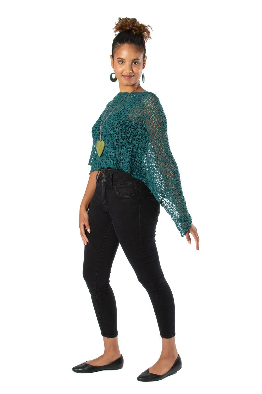 Woman wearing a green crochet top and black pants on a white background