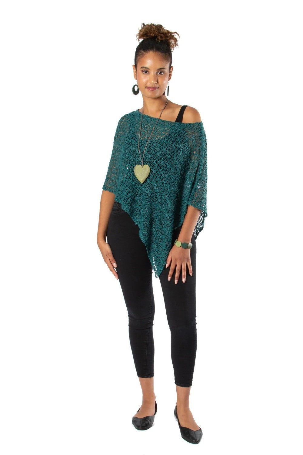 Woman wearing a green poncho and black leggings on a white background
