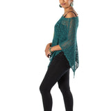 Woman wearing a green knitted poncho and black leggings on a white background