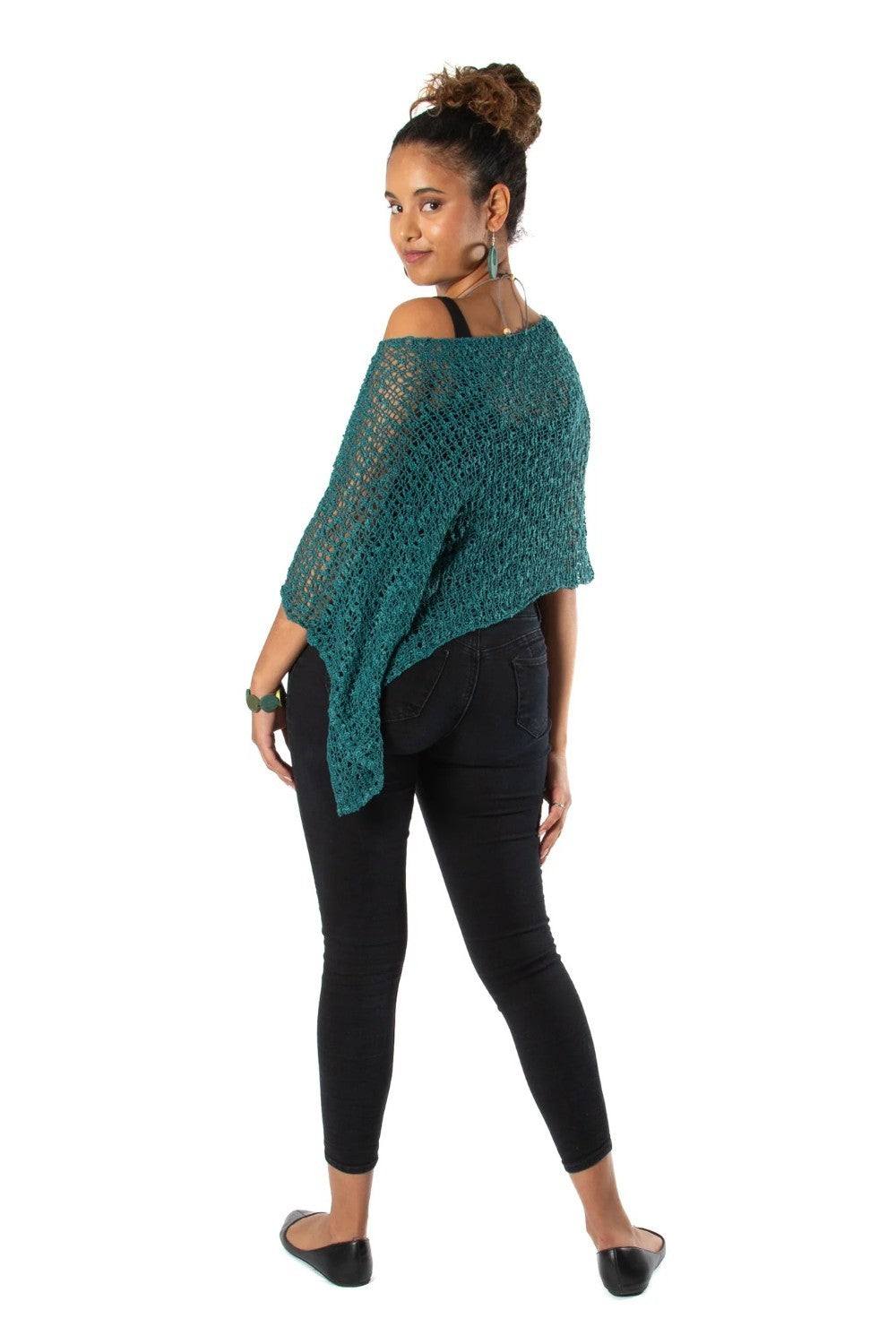 Woman wearing a green knitted poncho and black pants on a white background