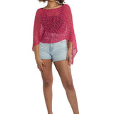 Woman wearing a pink crochet top and light blue shorts on a white background