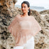Woman wearing a light crochet poncho with white jeans in an outdoor setting