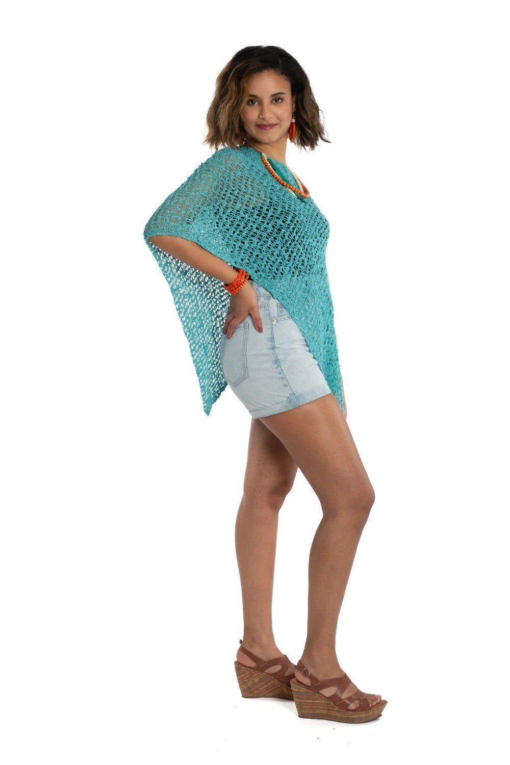 Woman wearing a turquoise knitted poncho on a white background