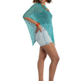 Woman wearing a turquoise knitted poncho on a white background