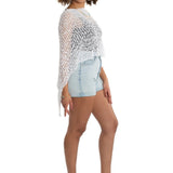 Woman wearing a white crochet top and denim shorts on a white background