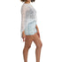 Woman wearing a white crochet top and denim shorts on a white background