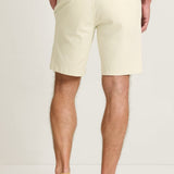 Person wearing beige shorts and white sneakers on a plain background