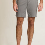 Person wearing gray shorts on a beige background