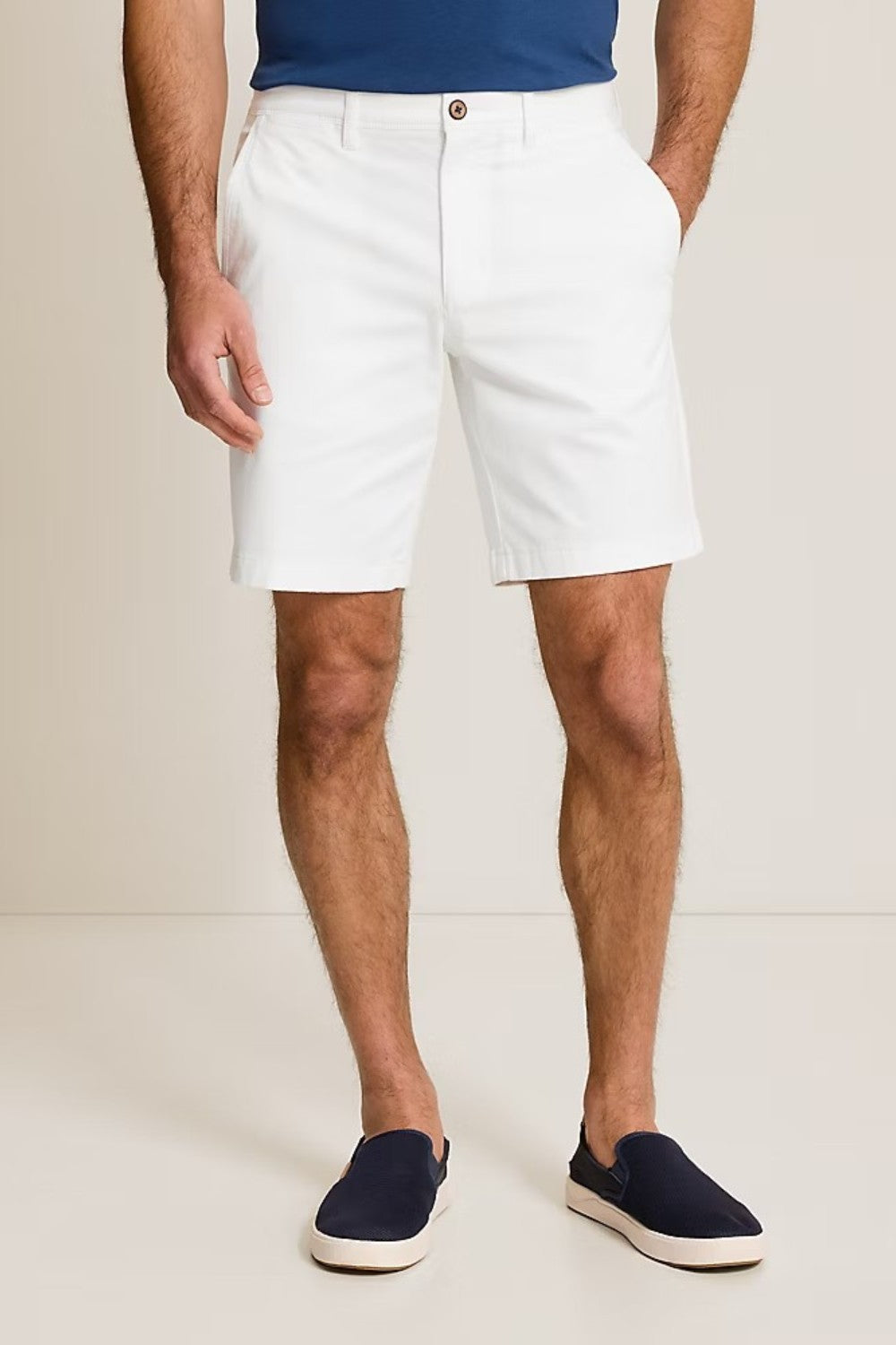 Person wearing white shorts and navy shoes on a plain background