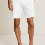 Person wearing white shorts and navy shoes on a plain background