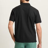 Man wearing a black polo shirt and green shorts on a beige background