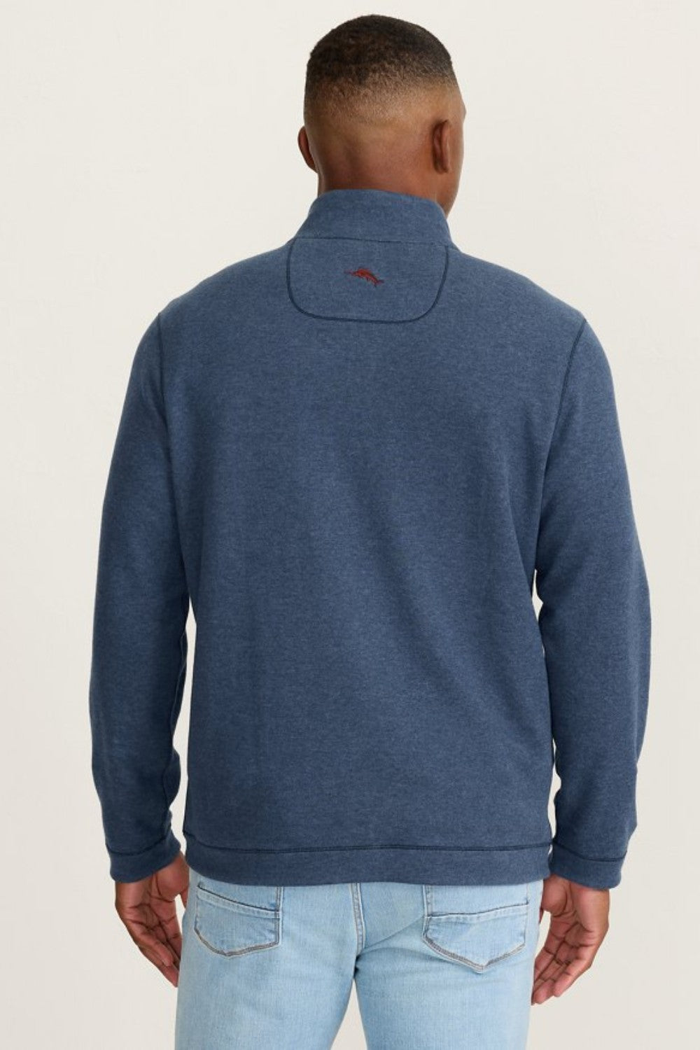 Person wearing a blue sweater with a visible brand logo on the back against a plain background