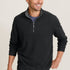 Man wearing a black half-zip sweater and green pants on a beige background