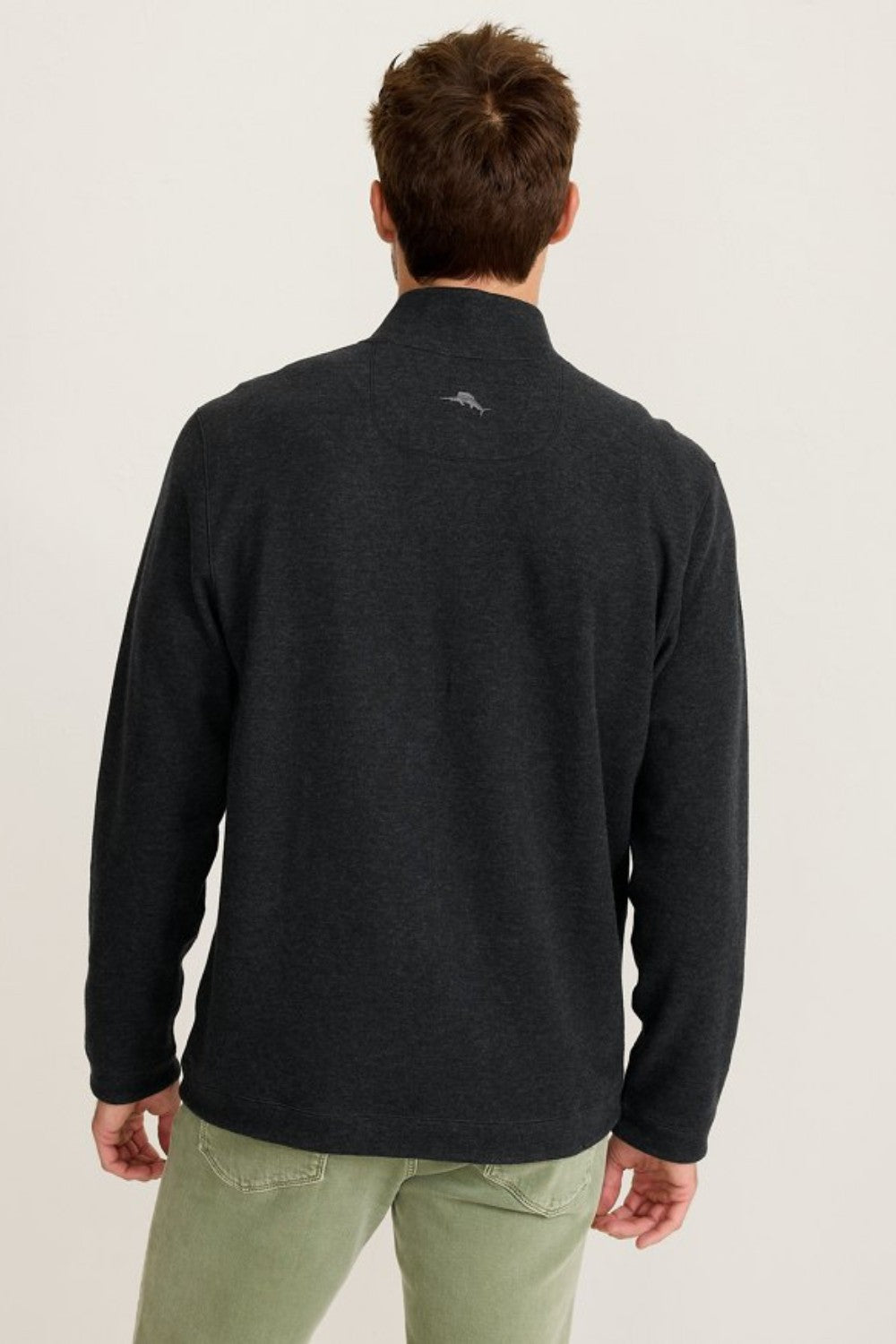 Man wearing a black sweater with a logo on the back against a light background
