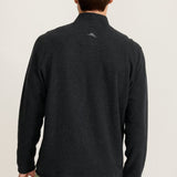Man wearing a black sweater with a logo on the back against a light background