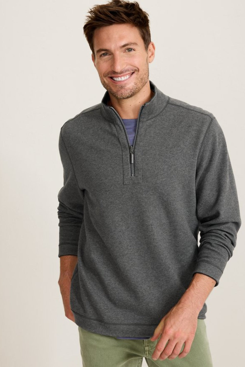 Man wearing a gray half-zip sweatshirt against a plain background