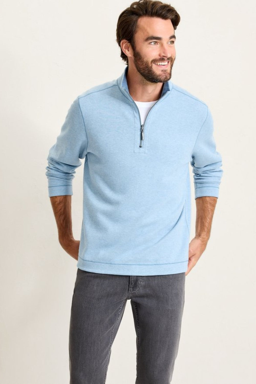 Man wearing a light blue pullover with a zipper on a plain background