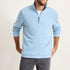 Man wearing a light blue pullover with a zipper on a plain background