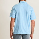 Man wearing a light blue polo shirt and gray shorts on a beige background