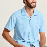 Man wearing a light blue short-sleeve shirt and gray shorts against a plain background