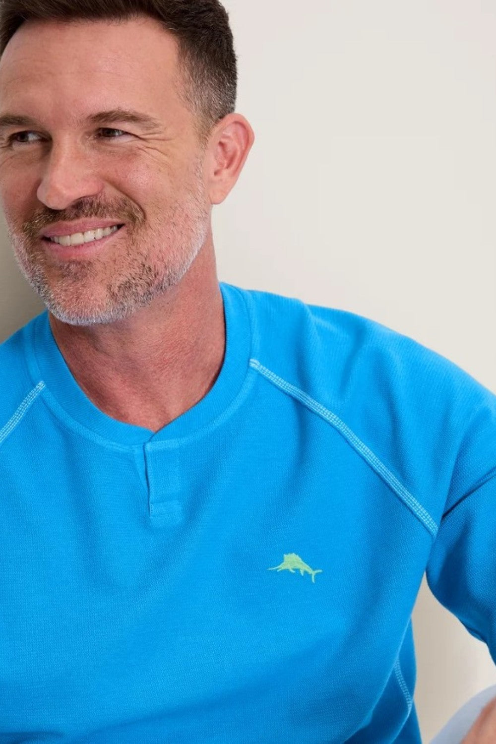 Man wearing a blue shirt with a logo on a plain background
