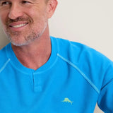 Man wearing a blue shirt with a logo on a plain background