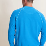 Man wearing a blue sweatshirt with white piping on a plain background