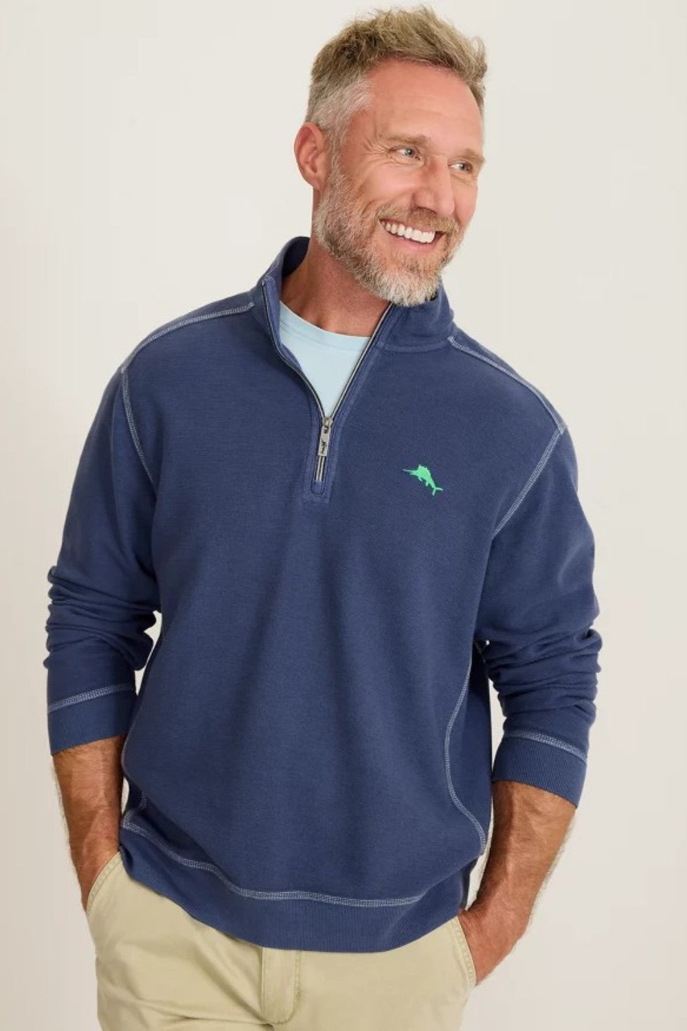 Man wearing a blue pullover with a logo on a light background
