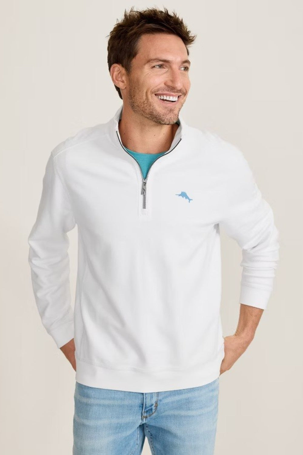 Man wearing a white quarter-zip sweatshirt with a logo on a beige background