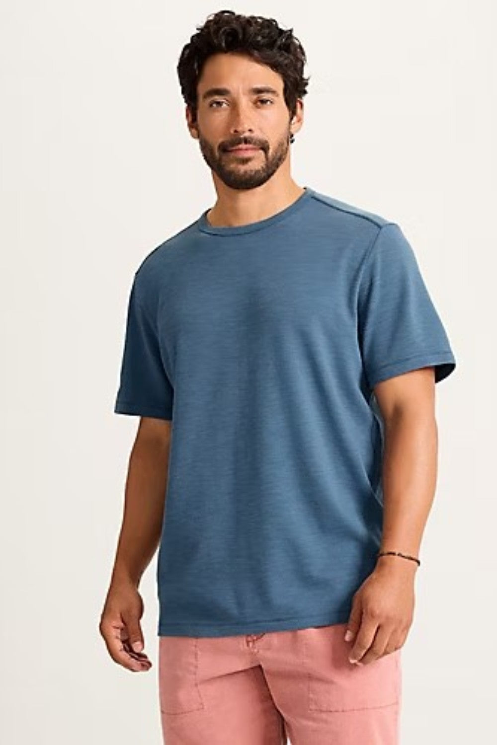 Man wearing a blue t-shirt and pink pants on a white background