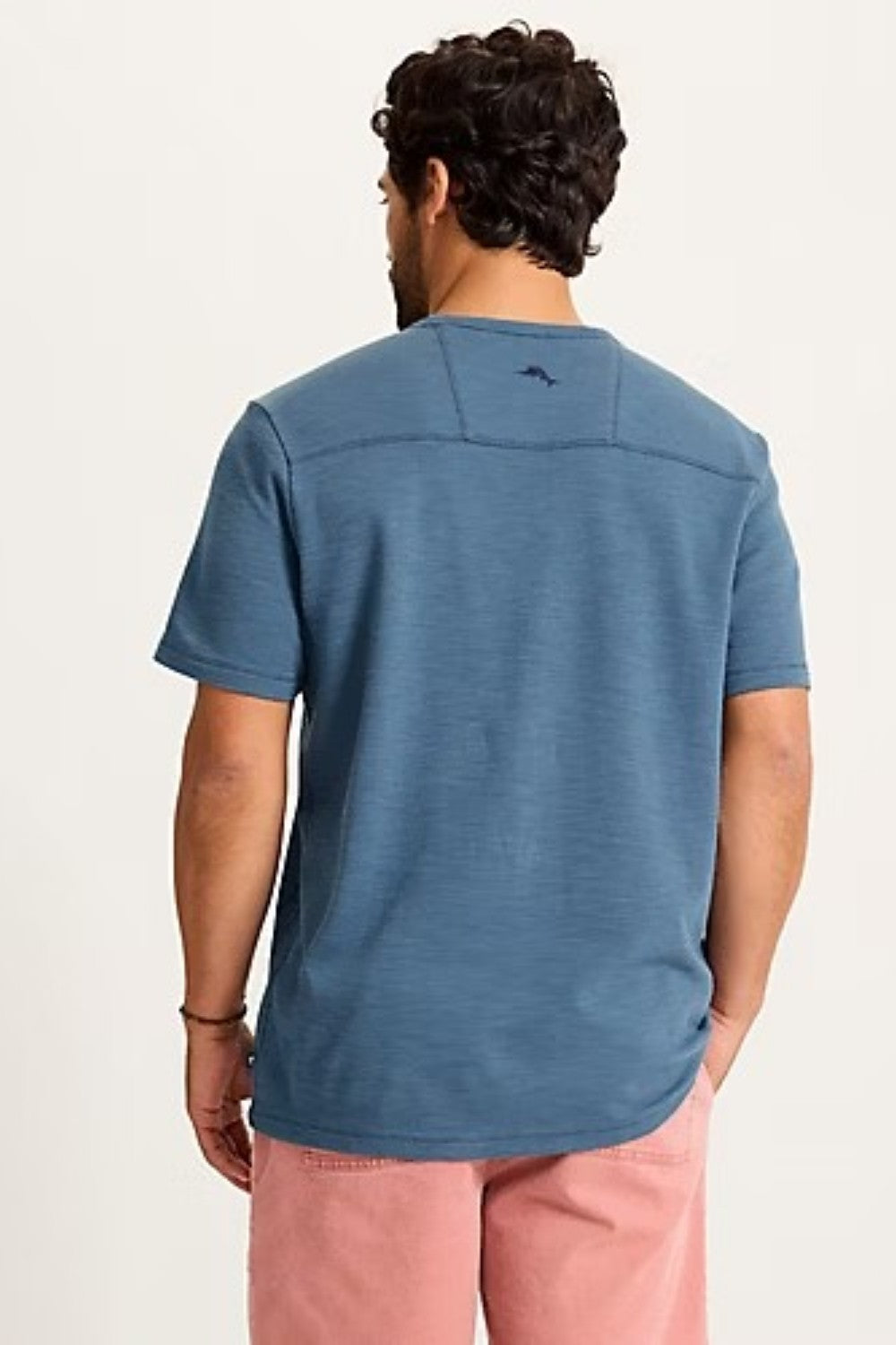 Man wearing a blue t-shirt with a logo on the back against a light background